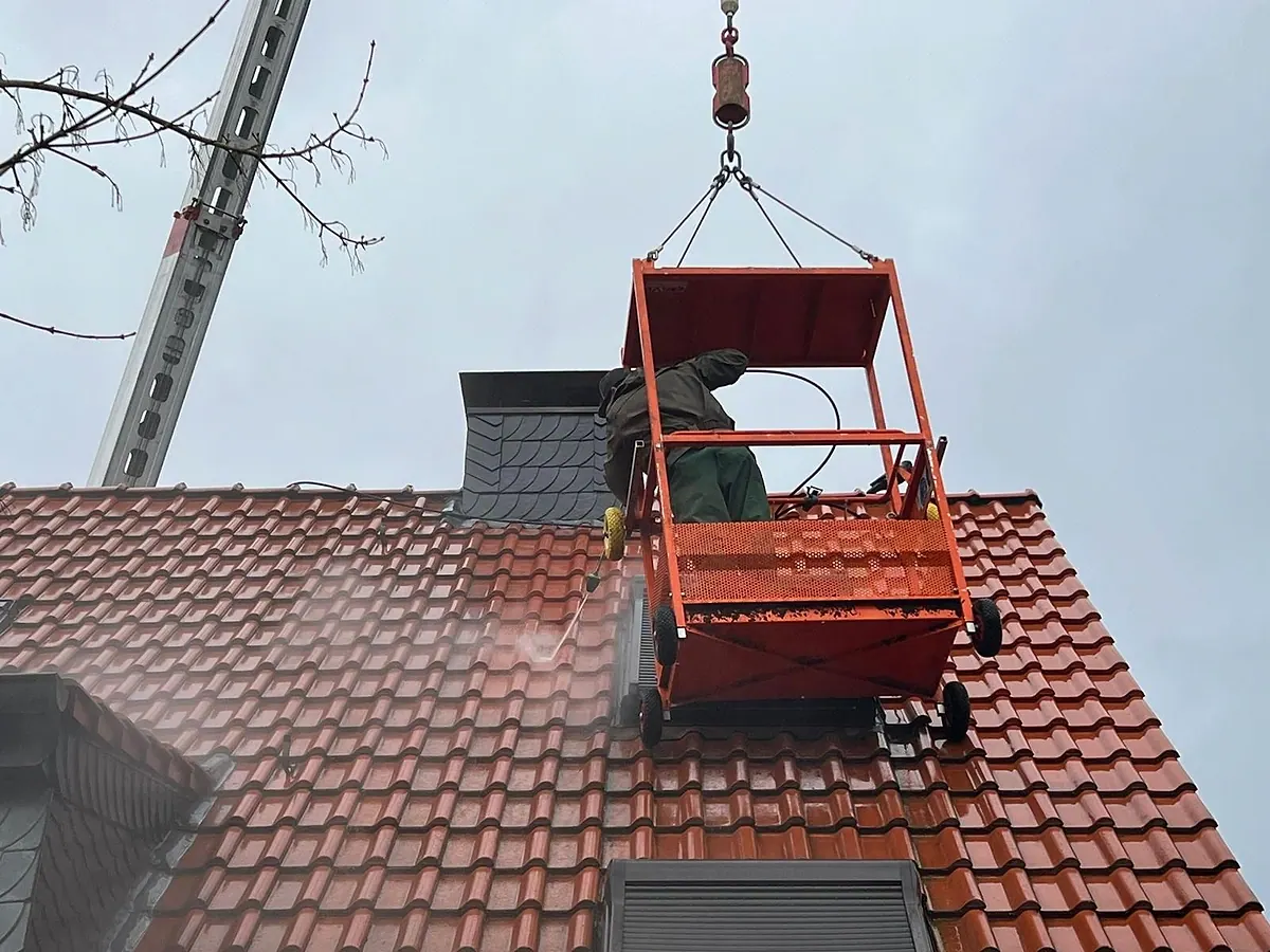 Dachreinigung eines Ziegeldachs aus dem Arbeitskorb am Kran